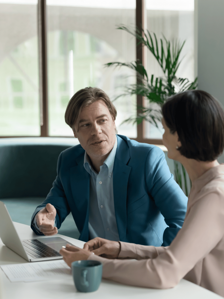 A man talking to a woman with a laptop and coffee in front of them