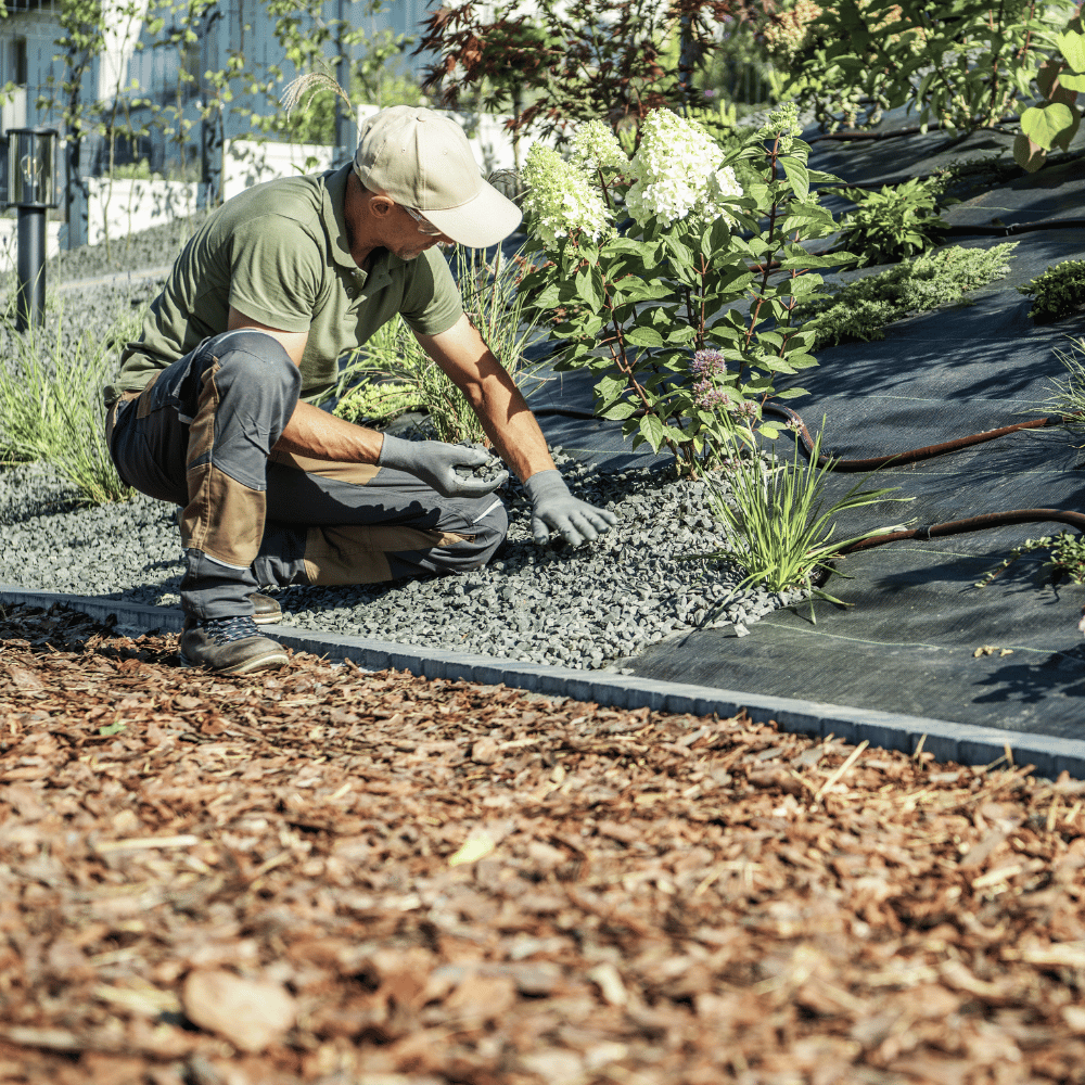 A man putting stone on top of a weed barrier